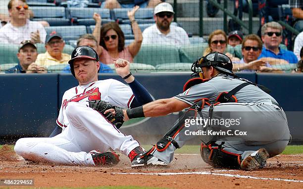 Freddie Freeman of the Atlanta Braves slides safely past the tag of Jeff Mathis of the Miami Marlins on a two-RBI single hit by Hector Olivera in the...
