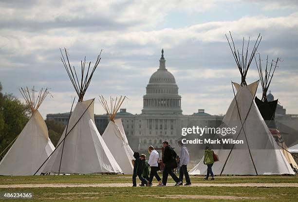 People walk past Indian Teepees that are on the National Mall as part of a protest against the Keystone pipeline April 23, 2014 in Washington, DC. As...