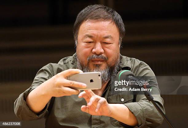 Chinese dissident artist Ai Weiwei takes a photo with his mobile phone as he attends a panel discussion at the Berlin International Literature...