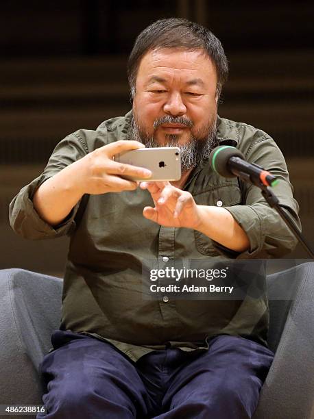 Chinese dissident artist Ai Weiwei takes a photo with his mobile phone as he attends a panel discussion at the Berlin International Literature...