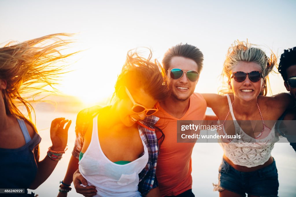 Friends dancing on beach in sunset