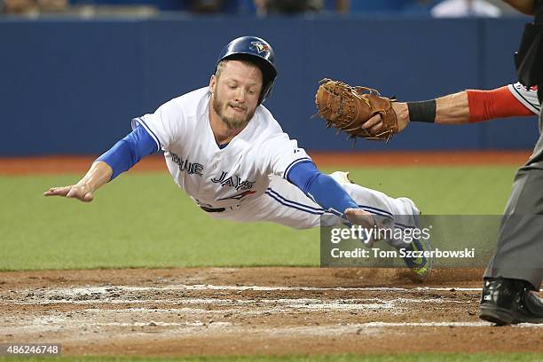 Josh Donaldson of the Toronto Blue Jays slides safely across home plate to score on a sacrifice fly in the second inning during MLB game action as...