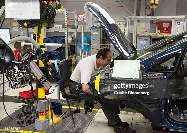 An employee works under the trunk of an Opel Corsa automobile at the Adam Opel AG factory, operated by General Motors Co. , in Eisenach, Germany, on...