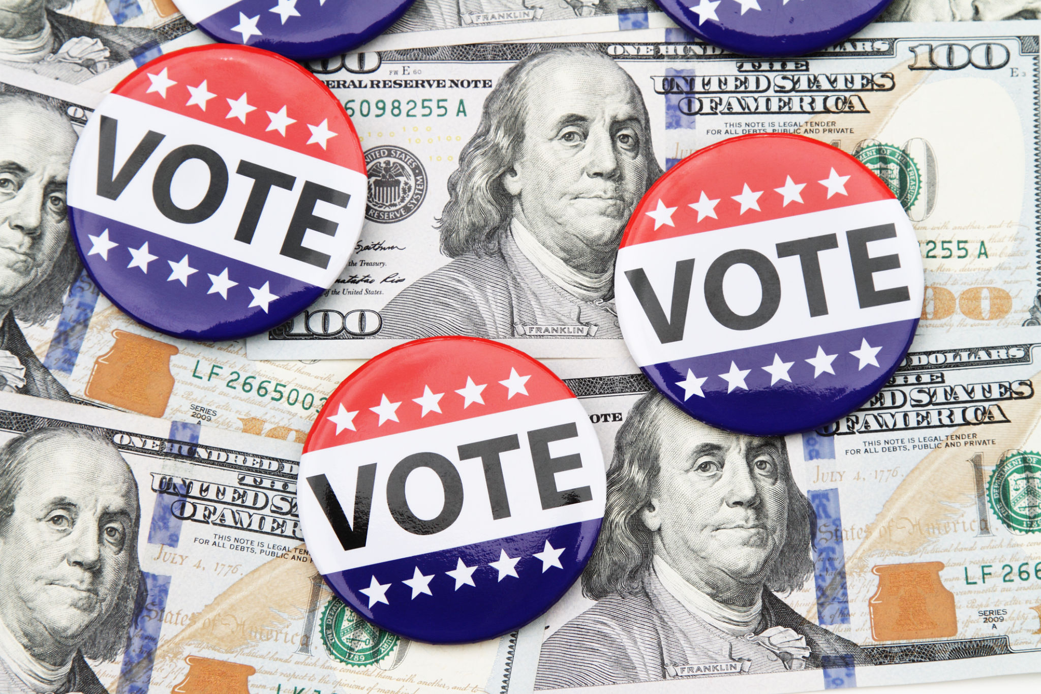 VOTE campaign buttons on top of hundred dollar bills VOTE campaign buttons on top of hundred dollar bills