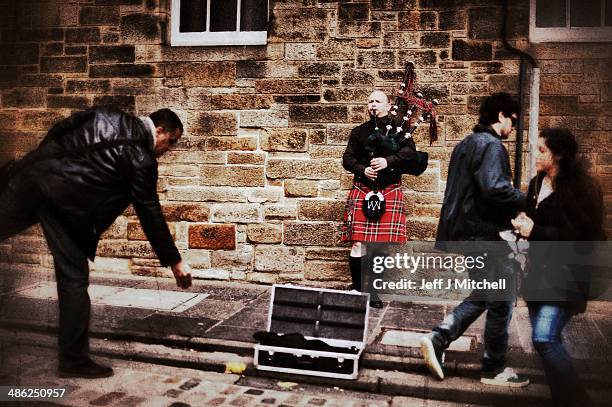 Man drops some money into a pipers case busking on the Royal Mile on April 23, 2014 in Edinburgh, Scotland. A referendum on whether Scotland should...