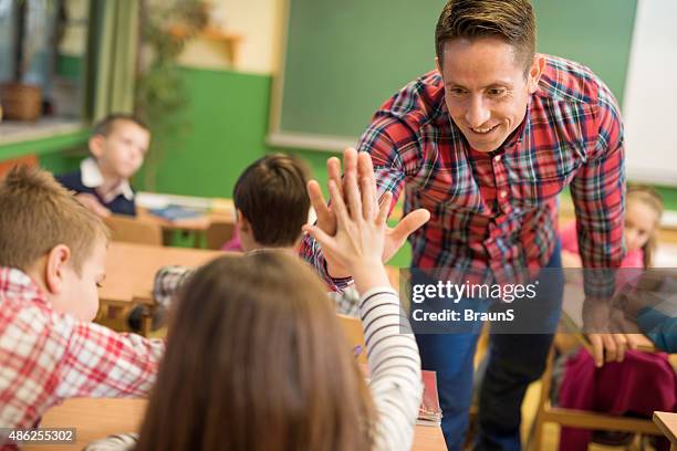 happy elementary teacher congratulating his student on good answer. - congratulating child stock pictures, royalty-free photos & images