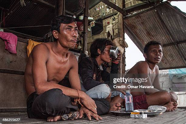 Three former fishermen drink rice wine in the floating village of Chong Kneas on April 23, 2014 in Siem Reap, Cambodia. Home to hundreds of thousands...