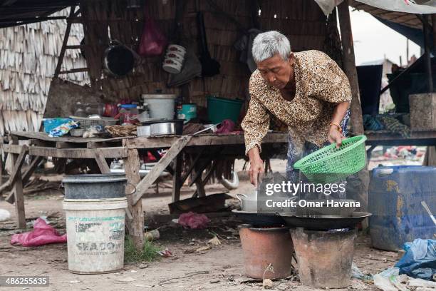 Resident of the village of Chong Kneas, where most of the residents are former fishermen, cooks dinner in her hut on April 23, 2014 in Siem Reap,...