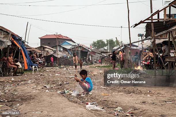 Young boy lights a fire using a bamboo stick in the only lane that cross the floating village of Chong Kneas during the dry season on April 23, 2014...