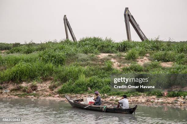 Family rides a boat near the floating village of Chong Kneas near the development area of a new tourist dock on April 23, 2014 in Siem Reap,...