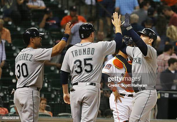 Logan Morrison of the Seattle Mariners is greeted by Franklin Gutierrez and Mark Trumbo of the Seattle Mariners after Morrison hit a three-run home...