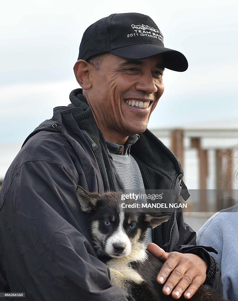 US President Barack Obama holds a puppy while visiting musher John ...