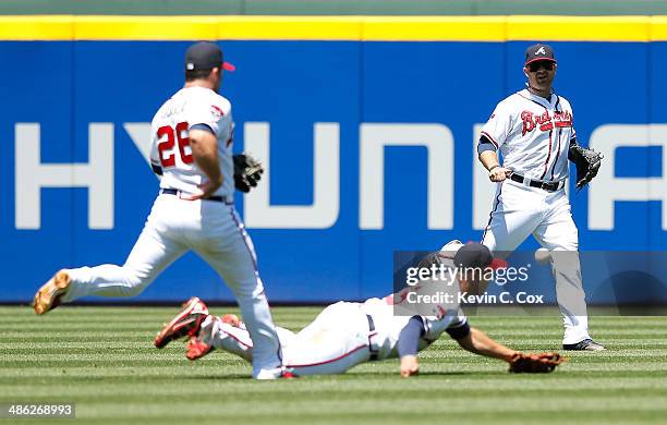 Ryan Doumit, Dan Uggla and Andrelton Simmons of the Atlanta Braves chase after a fly ball that turned into a RBI double for Giancarlo Stanton of the...