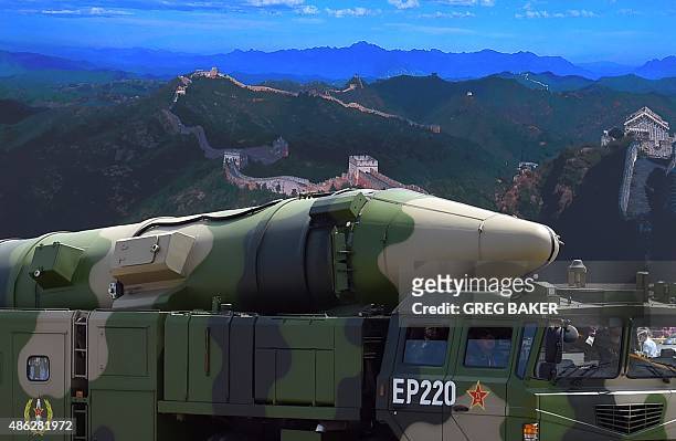 Military vehicle carries DF-21D missile past a display screen featuring an image of the Great Wall of China at Tiananmen Square in Beijing on...