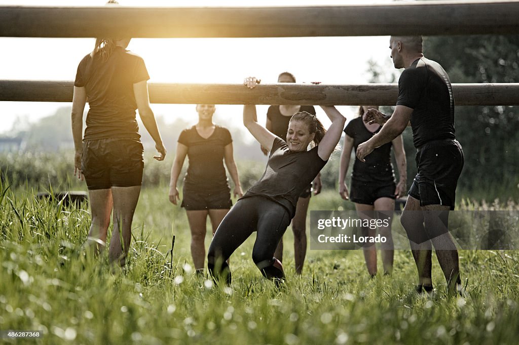 Coach helping group of women to cross wooden obstacle