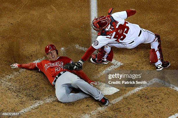 Mike Trout of the Los Angeles Angels of Anaheim slides safely into home plate as catcher Jose Lobaton of the Washington Nationals cannot make the tag...