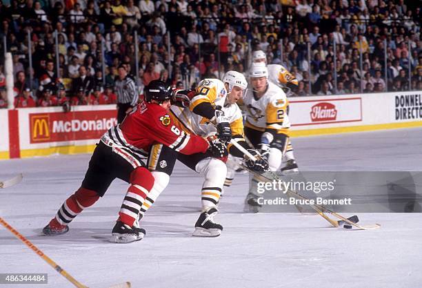 Ron Francis of the Pittsburgh Penguins controls the puck as Frantisek Kucera of the Chicago Blackhawks goes for the poke check during Game 1 of the...