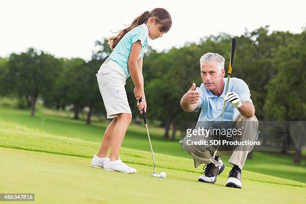 little girl taking golf lessons from senior golf pro instructor - golf clubhouse stockfoto's en -beelden