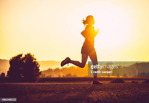 adult woman running outdoors - rennen stockfoto's en -beelden