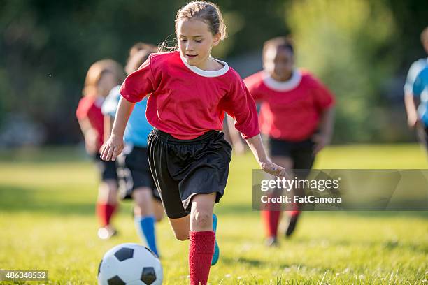girl pone a un campo de bola - playing football fotografías e imágenes de stock