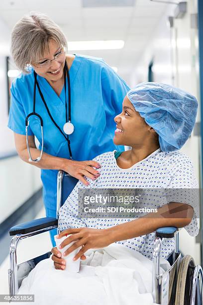 krankenschwester mit patienten auf einen rollstuhl zur erholung zimmer nach operation - rollstuhl schieben stock-fotos und bilder