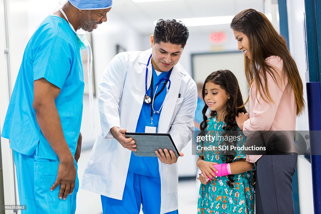 Surgeons talking to pediatric patient's mother in hospital hallway