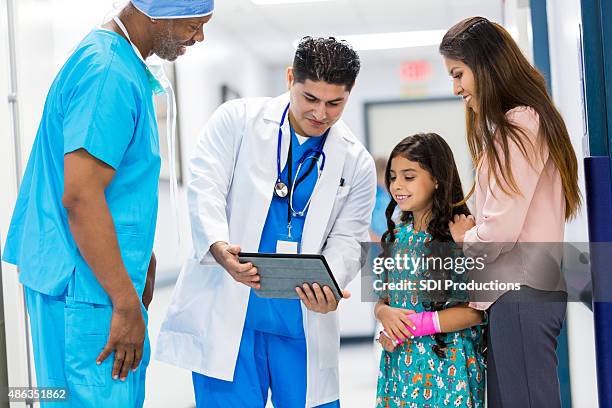 surgeons talking to pediatric patient's mother in hospital hallway - x ray arm stock pictures, royalty-free photos & images