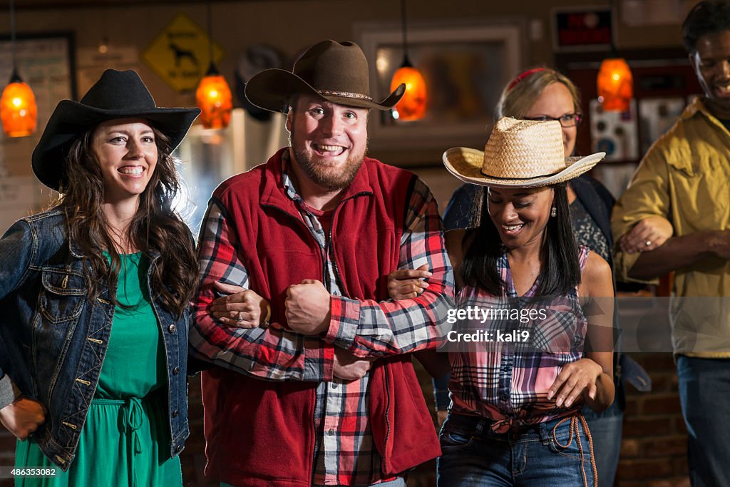 Group of multiracial friends dancing in cowboy hats