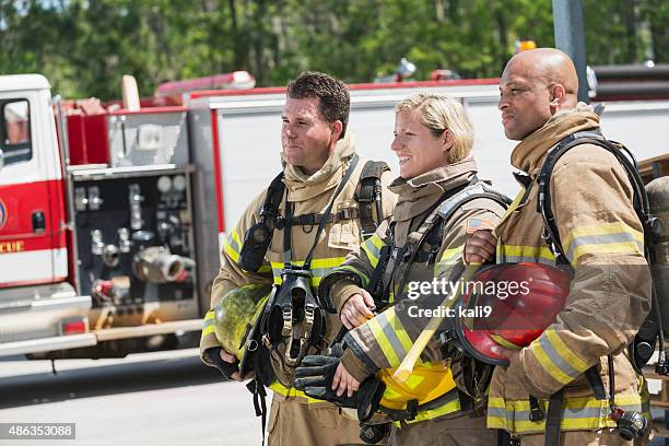 female firefighter with two male colleagues - firefighter stock pictures, royalty-free photos & images