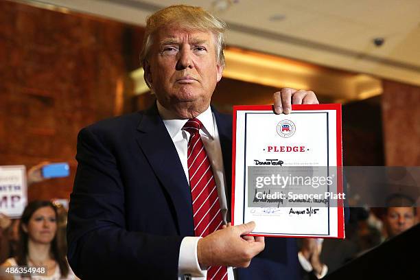 Presidential front-runner Donald Trump holds up a pledge at a news conference in Manhattan after he signed the pledge Thursday to support the...