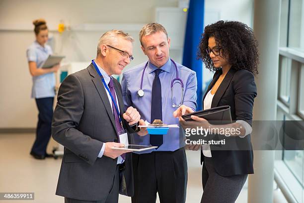 hospital administrator-team - caucasian doctor and nurse using tablet computer stock-fotos und bilder