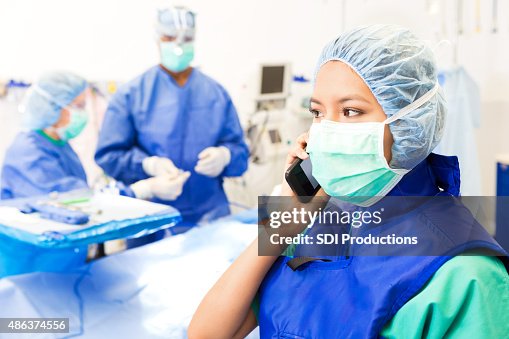 OP-Techniker oder Krankenschwester mit Anruf in Operationssaal OP-Techniker oder Krankenschwester mit Anruf in Operationssaal