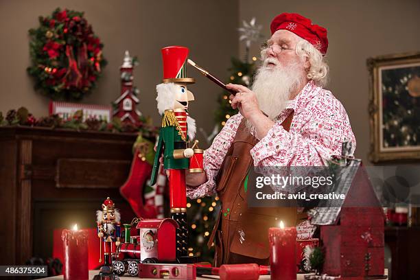santa claus painting nutcracker in toy shop - santas workshop stock pictures, royalty-free photos & images