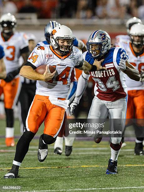 Travis Lulay of the BC Lions protects the ball from Kyries Hebert of the Montreal Alouettes during the CFL game at Percival Molson Stadium on...