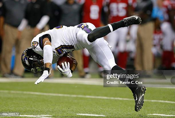 Asa Jackson of the Baltimore Ravens trips and flips over as he returns a punt against the Atlanta Falcons at Georgia Dome on September 3, 2015 in...