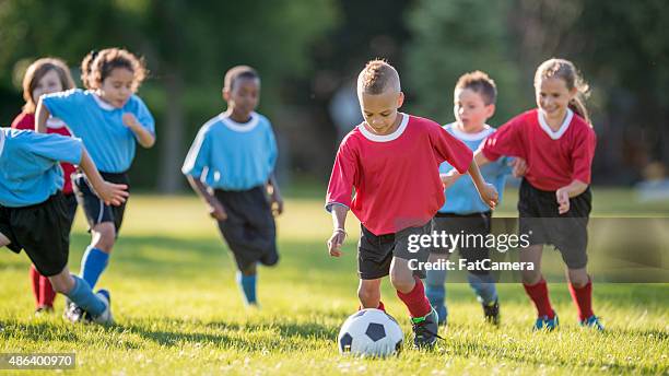 boy kicking a soccer ball - child dribbling soccer ball stock pictures, royalty-free photos & images