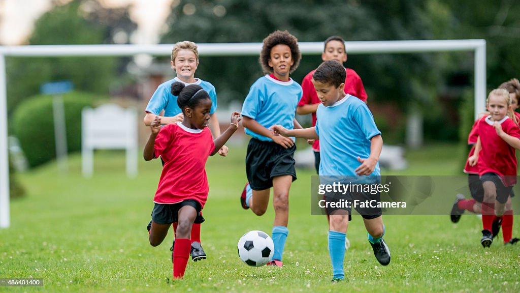 Kinder verfolgen einen Fußball bei einem Spiel