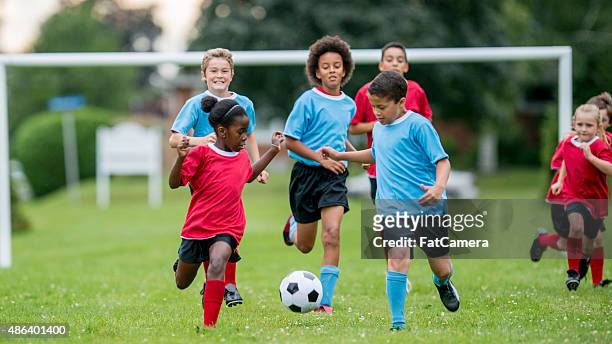 kinder verfolgen einen fußball bei einem spiel - sportbegriff stock-fotos und bilder