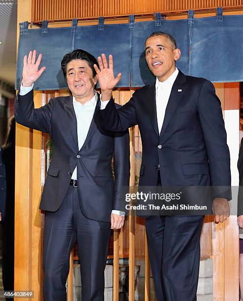 President Barack Obama and Japanese Prime Minister Shinzo Abe wave to media reporters in front of the three-star sushi restaurant 'Sukiyabashi Jiro'...