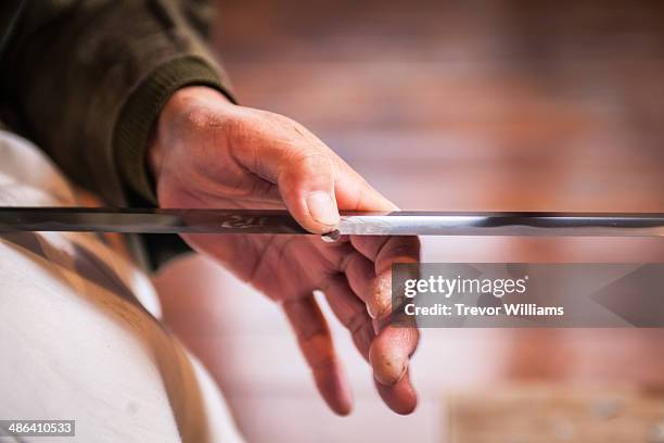 a craftsmen sharpens a traditional japanese sword - traditional craftsman stock pictures, royalty-free photos & images