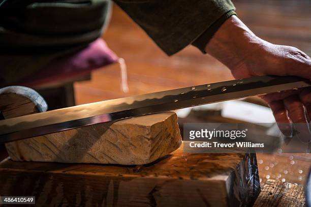 a craftsmen sharpens a traditional japanese sword - sword in the stone stock-fotos und bilder
