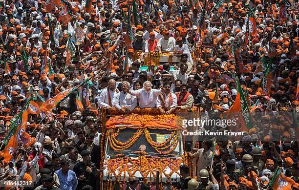 Flowers are thrown as BJP leader Narendra Modi waves to supporters as he rides on an open truck on his way to filing his nomination papers on April...