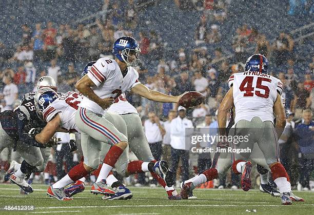 Ricky Stanzi of the New York Giants prepares to hand the ball to Henry Hynoski in the fourth quarter in a pre-season game against the New England...