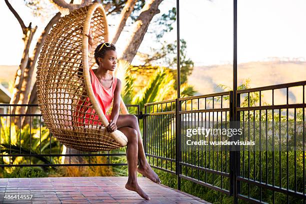 woman sitting in a hanging chair - schommelen bungelen stockfoto's en -beelden