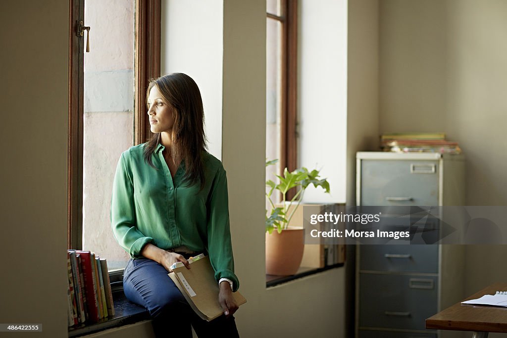 Portrait of business woman sitting in windowsill