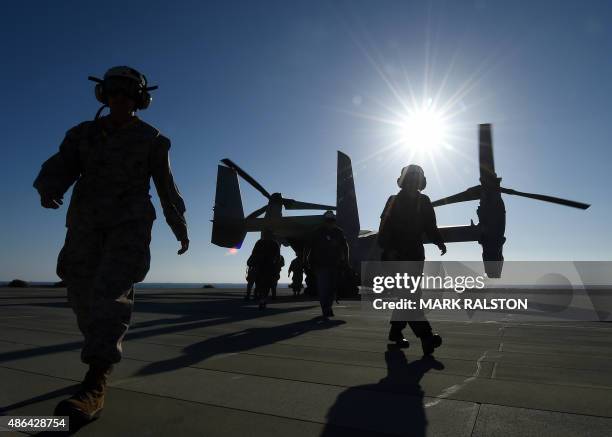 Crewmen leave a US Marine MV-22 Osprey after returning from the Japan Maritime Self-Defense Force ship JS Hyuga during the joint Dawn Blitz 2015...