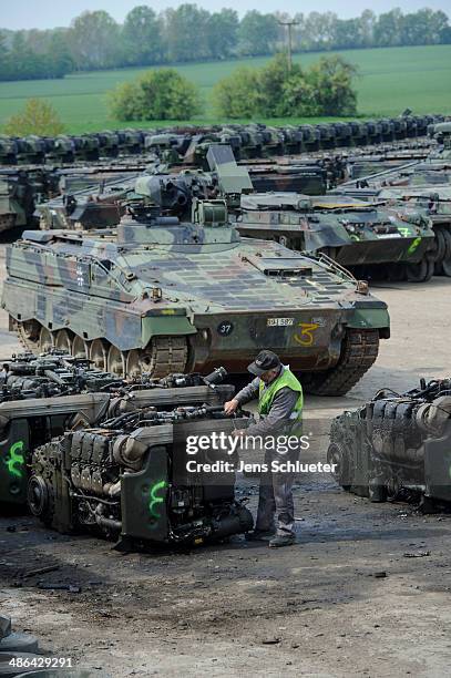 Technician uses a tool to cut the engine of a Leopard main battle tank that once belonged to the Bundeswehr, in the background are Marder light...