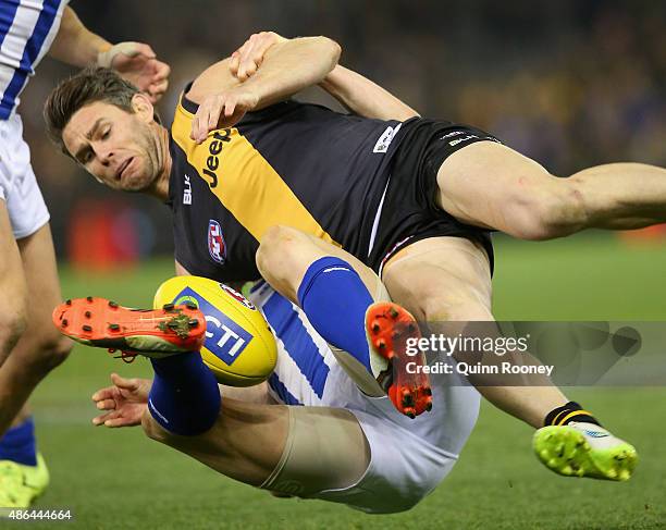 Chris Newman of the Tigers is tackled by Jack Ziebell of the Kangaroos during the round 23 AFL match between the Richmond Tigers and the North...