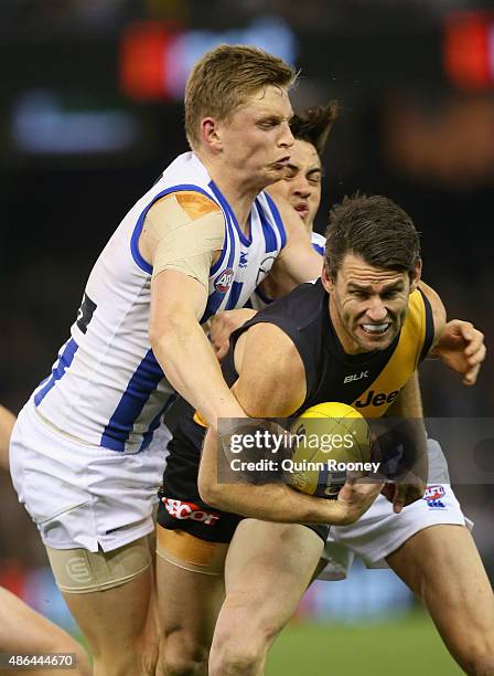 Chris Newman of the Tigers is tackled by Jack Ziebell of the Kangaroos during the round 23 AFL match between the Richmond Tigers and the North...