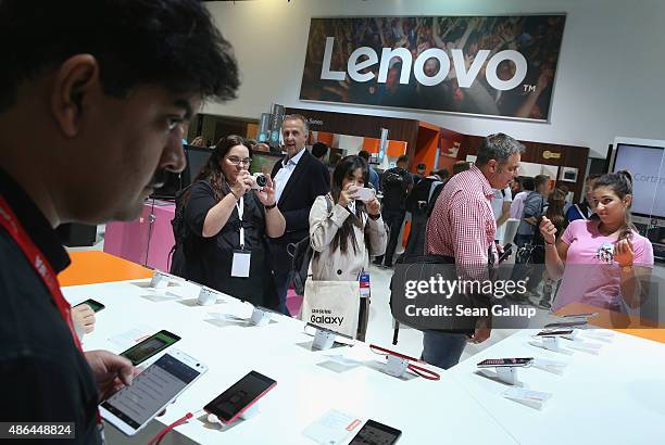 Visitors look at smartphones at the Lenovo stand at the 2015 IFA consumer electronics and appliances trade fair on September 4, 2015 in Berlin,...